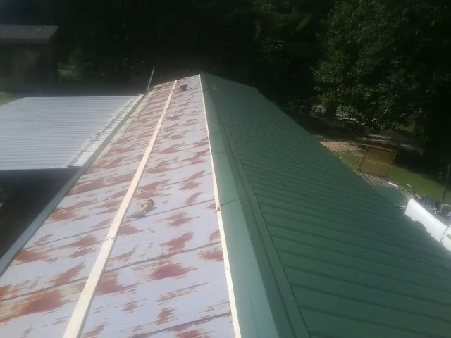 Old rusted panels beside newly installed green metal roofing — Wind Damage Roof Repair by Roofing Brothers in Sunset