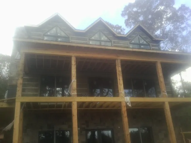 Dormers and porch framing on a large log home under construction — Roof Coating work by our crew in Sunset