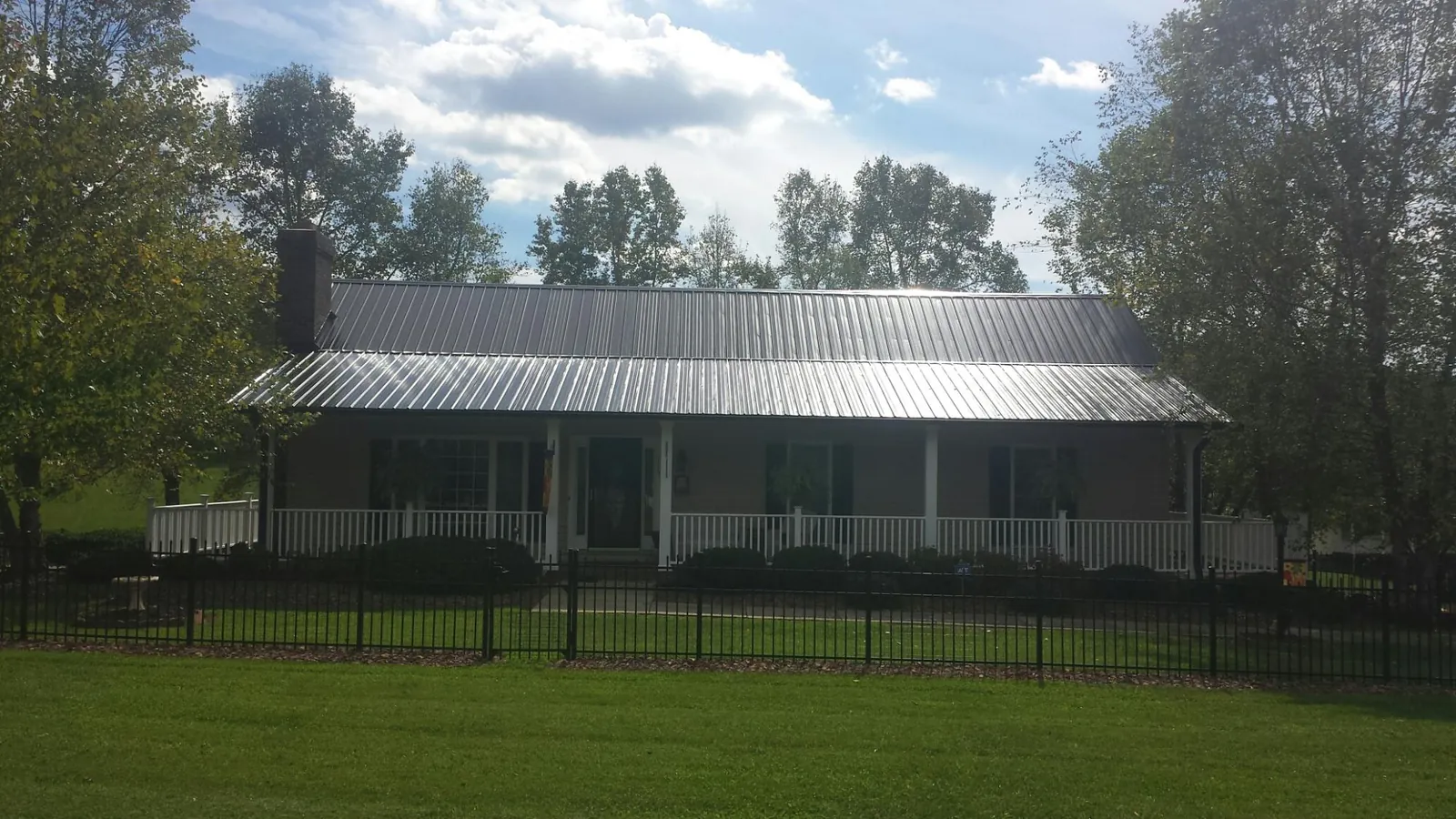 Gray metal roof on a brick ranch with a full width front porch — Gutter Guard Installation work by our crew in Sunset