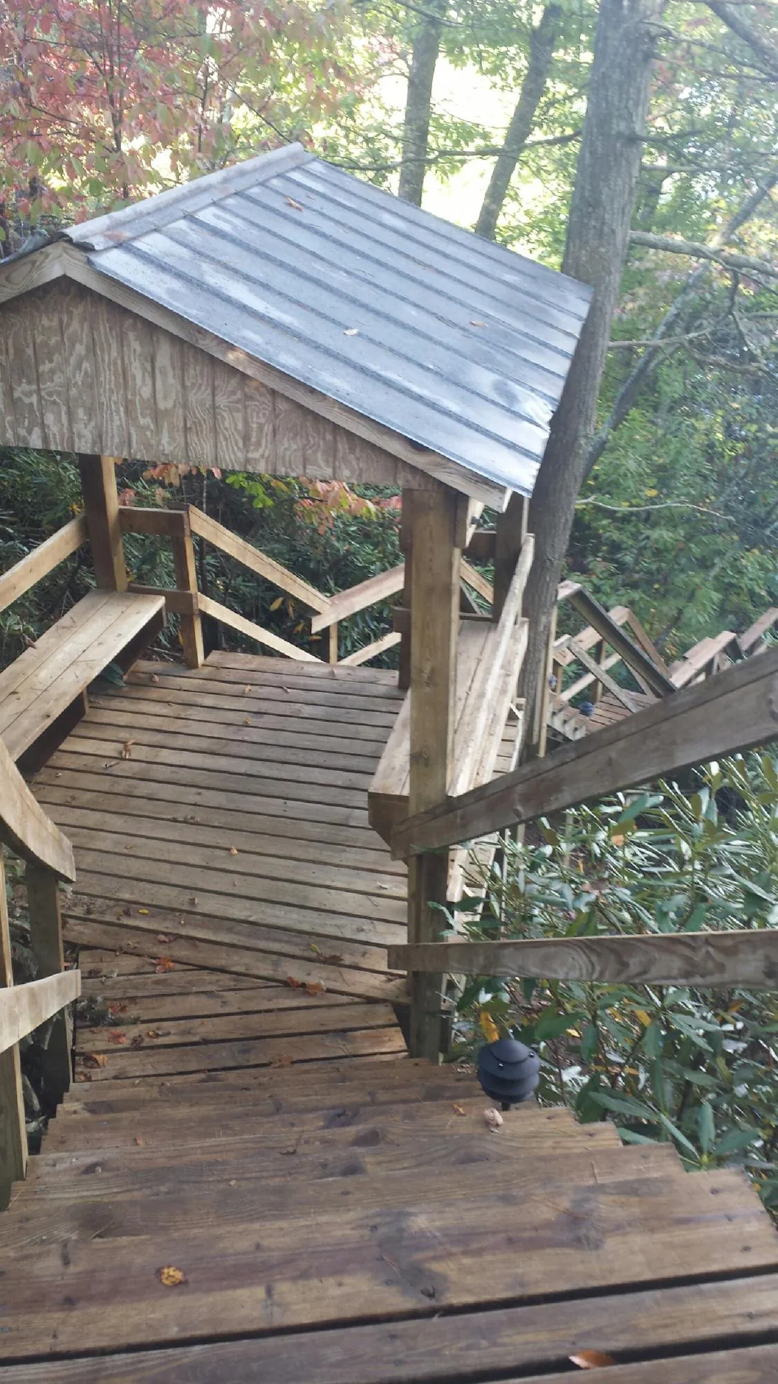 Metal roofed shelter over wooden steps on a wooded walkway — Skylight Repair & Installation work by our crew in Sunset